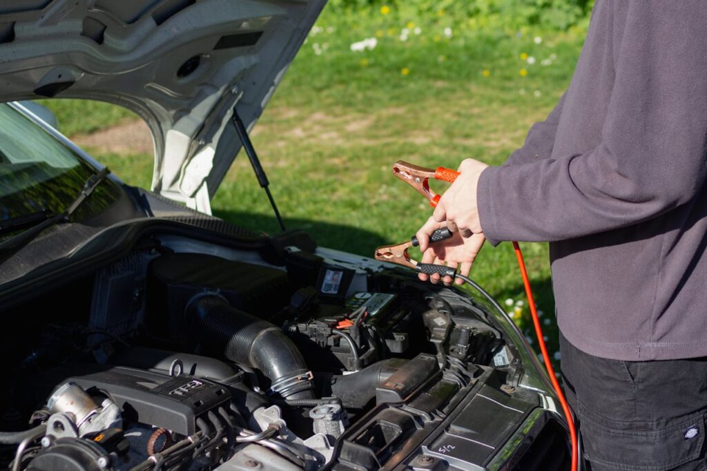 Crafting Captivating Headlines: Your awesome post title goes here Man using jumper cables on car engine outdoors on a sunny day. Vehicle maintenance and repair concept.